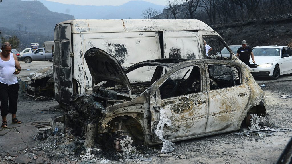People inspect burnt vehicles after raging wildfires, in Bouira, 100 km from Algiers, Algeria, Monday, July 24, 2023. Wildfires raging across Algeria have killed at least 25 people, including soldiers trying to get the flames under control in the face of high winds and scorching summer temperatures, government ministries said Monday. (AP Photo) XMS101