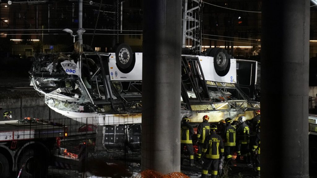 Italian firefighters work at the scene of a passenger bus accident in Mestre, near Venice, Italy, Wednesday, Oct. 4, 2023. According to local media, the bus fell a few meters from an elevated rod before crashing Tuesday close to Mestre's railway tracks, where it caught fire. (AP Photo/Antonio Calanni) MES113