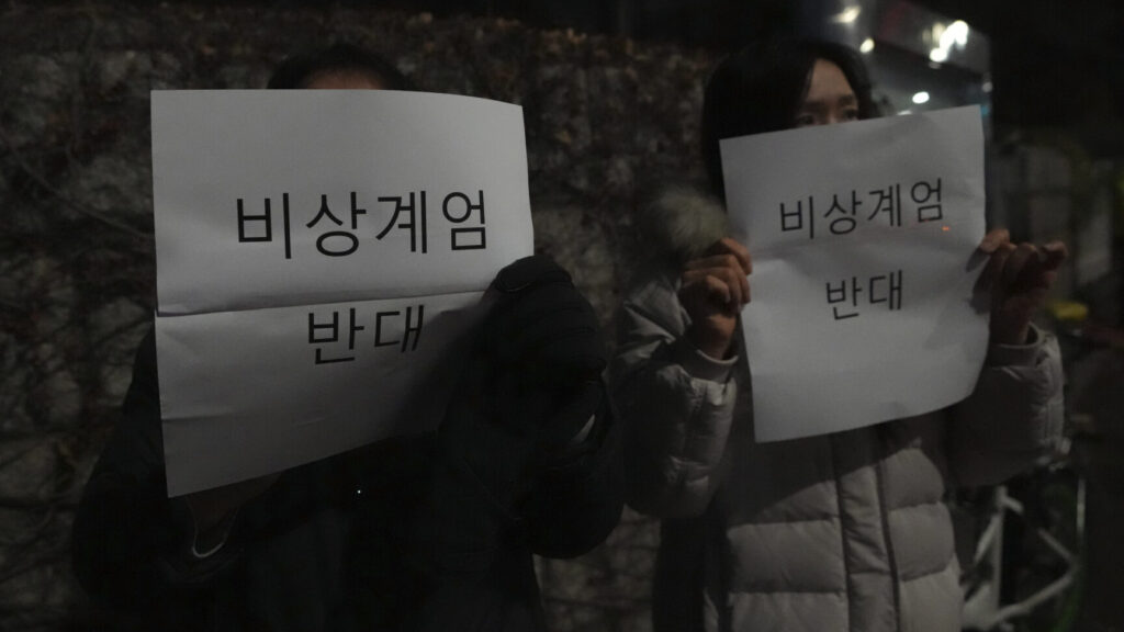 People hod signs reading "oppose emergency martial law", in front of the National Assembly in Seoul, South Korea, Tuesday, Dec. 3, 2024. (AP Photo/Lee Jin-man) LJM107