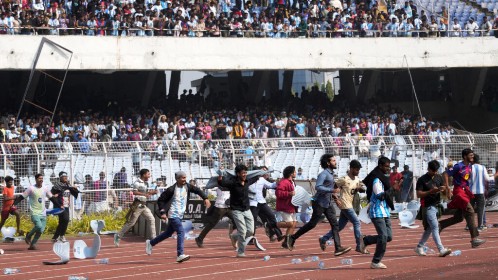 Indian fans vandalize stadium chairs as they run on to the field after failing to get a glimpse of Argentine soccer star Lionel Messi at the Salt Lake Stadium, in Kolkata, India, Saturday, Dec. 13, 2025. (AP Photo/Bikas Das) XBD108
