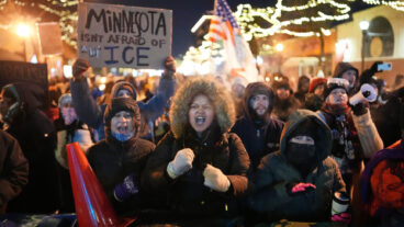 Protesters chant and bang on trash cans as they stand behind a makeshift barricade during a protest in response to the death of 37-year-old Alex Pretti, who was fatally shot by a U.S. Border Patrol officer earlier in the day, Saturday, Jan. 24, 2026, in Minneapolis. (AP Photo/Adam Gray)  MNSS623