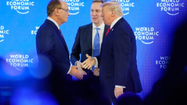 President Donald Trump is welcomed by Forum's President Borge Brende and Forum's Co-Chair Larry Fink on the podium before his speech during the Annual Meeting of the World Economic Forum in Davos, Switzerland, Wednesday, Jan. 21, 2026. (AP Photo/Markus Schreiber) MME111
