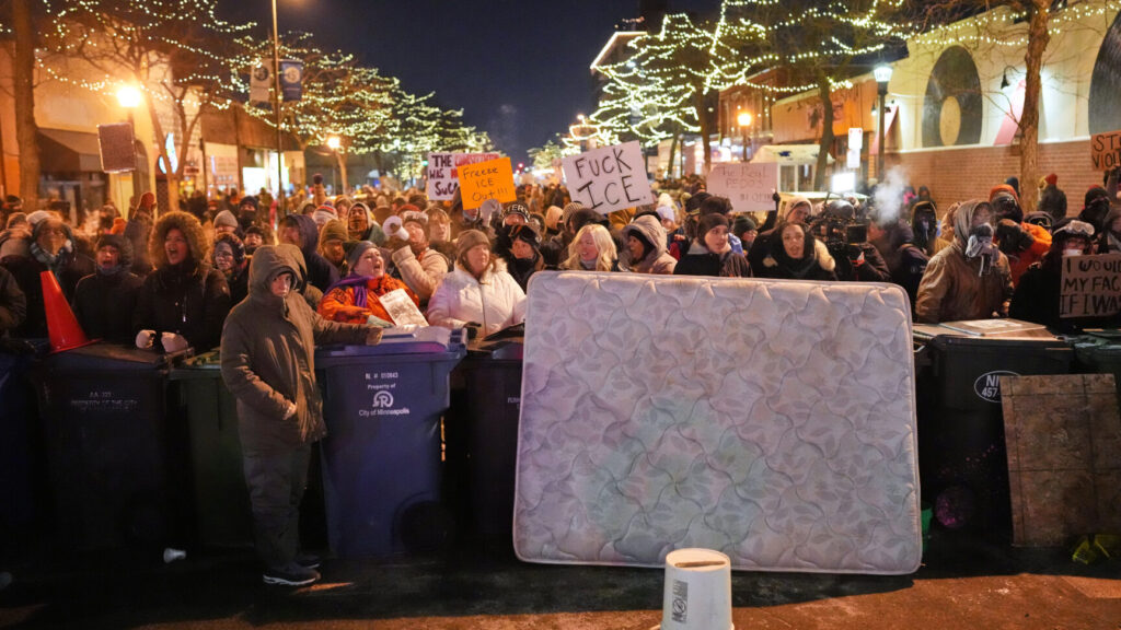 Protesters stand behind a makeshift barricade during a protest in response to the death of 37-year-old Alex Pretti, who was fatally shot by a U.S. Border Patrol officer earlier in the day, Saturday, Jan. 24, 2026, in Minneapolis. (AP Photo/Adam Gray) MNSS621