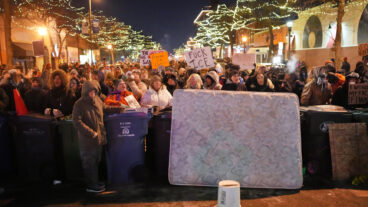 Protesters stand behind a makeshift barricade during a protest in response to the death of 37-year-old Alex Pretti, who was fatally shot by a U.S. Border Patrol officer earlier in the day, Saturday, Jan. 24, 2026, in Minneapolis. (AP Photo/Adam Gray)  MNSS621