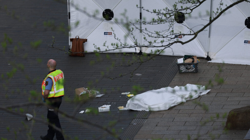A policeman stands next to a body bag after a car crashed into several people in Leipzig, Germany, Monday, May 4, 2026. (Sebastian Willnow/dpa via AP) DSOB107