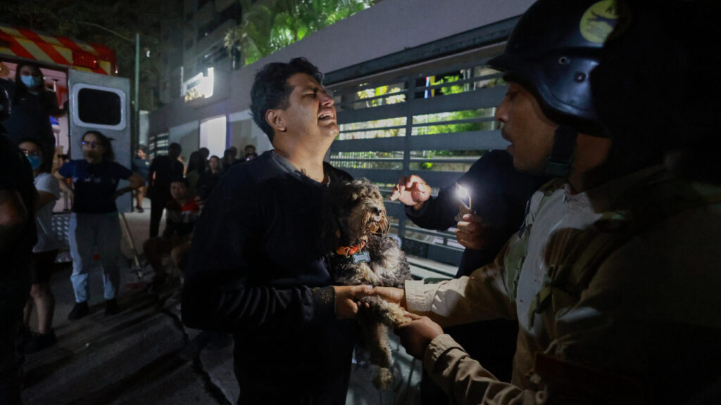 A man holding a dog cries after an earthquake in Caracas, Venezuela, Wednesday, June 24, 2026. (AP Photo/Javier Campos) XRM503