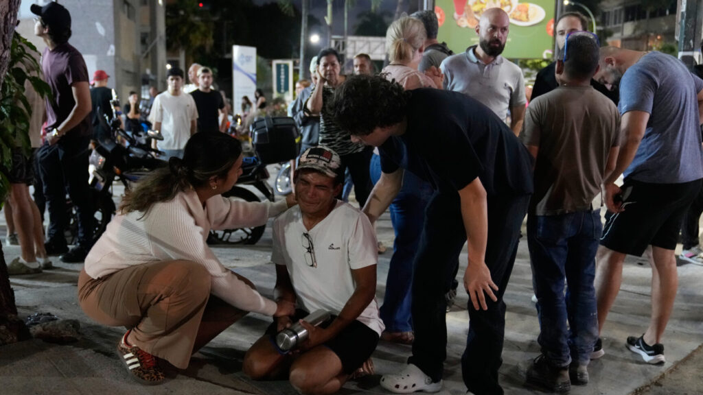 Residents console a man outside their homes after successive earthquakes, in Caracas, Venezuela, Wednesday, June 24, 2026. (AP Photo/Ariana Cubillos) XRM446