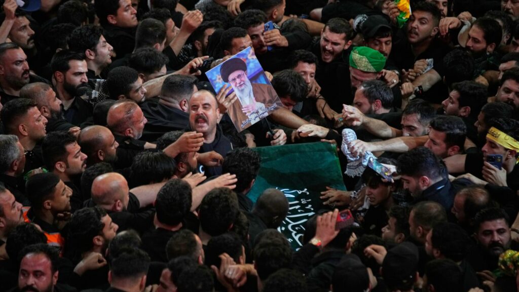 The coffin of the late Iranian Supreme Leader Ayatollah Ali Khamenei is carried through a tightly packed crowd as mourners jostle to reach and touch it outside the Imam Hussein Shrine in Karbala, Iraq, early Thursday, July 9, 2026. (AP Photo/Khalil Hamra) XEM135