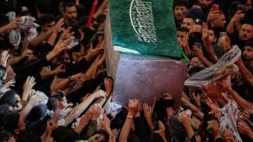 The coffin of the late Iranian Supreme Leader Ayatollah Ali Khamenei is carried through a crowd as mourners jostle to reach and touch it outside the Imam Hussein Shrine in Karbala, Iraq, early Thursday, July 9, 2026. (AP Photo/Khalil Hamra)  XEM130